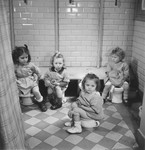 Four little girls sit on the potty in the Petit Monde children's home.