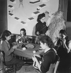A group of girls makes hand crafts with string in an unidentified post-war OSE children's home.