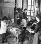 Two children help prepare food in the kitchen of an unidentified post-war OSE children's home.