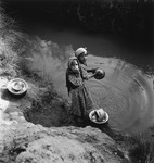Two Morrocan Jewish girls wash dishes in a lake or river in the Los Arenas camp while waiting to immigrate to Palestine.