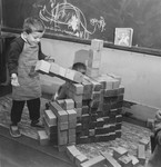 A young boy builds with blocks in a classroom in the Petit Monde children's home.