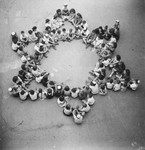 A large group or children sit in a star of David formation in an unidentified post-war OSE children's home.