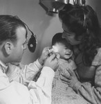A physician looks into the ear of a sick infant in an OSE health clinic.