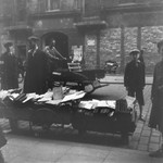 A vendor sells used books on a street in the Warsaw ghetto.