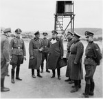 SS-Brigadefuhrer Richard Gluecks, the Inspector of Concentration Camps, stands carrying a briefcase with other SS men on an official visit to Gross-Rosen.
