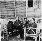 SS officers sit outside a building at the Gross-Rosen concentration camp laughing with a dog and a monkey.