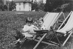 Two young children sit next to each other on canvas lawn chairs on a grassy field.