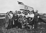Jewish displaced persons n the Landsberg camp gather for a group portrait underneath a large Israeli flag.