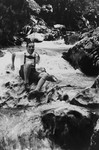 Close-up portrait of a German-Jewish man wearing lederhosen riding the whitewater of a mountain stream.