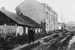 A man walks down a muddy street of an unidentified town under German occupation.