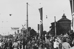 German citizens crowd together on a street in Nuremberg bedecked with Nazi flags.