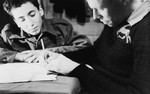 Two teenage boys write in a notebook in a boarding school in Switzerland.