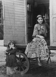 A Romani girl seated in her caravan doorway, with a young girl standing alongside.