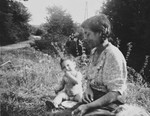A young Romani woman and child are seated on the grass, in wartime Belgium.