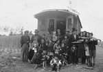 A group of Roma poses in front of a caravan.