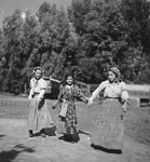 Three young Romani women walk together along a road.