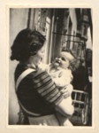 Page from a baby book showing Ernestine (Ily) Merei holding her infant son John on their balcony.