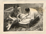 Page from a baby album showing Ernest (Erno) and Ernestine (Ily) Merei playing outdoors with their infant John.