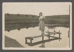 Fania Szwarcman stands on a small wooden structure on a river in prewar Aleksandria