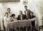 The Goldschmidt family poses around a table.

Riva Szrajer  (nee Goldschmidt) is standing behind the chairs (left).